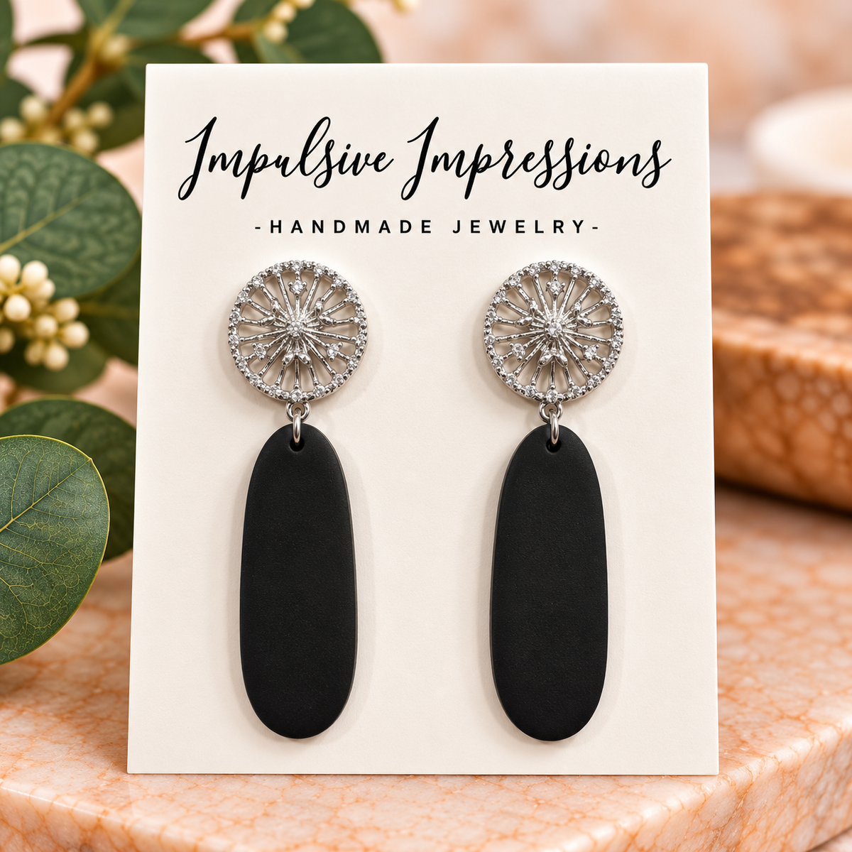 Black polymer clay elongated drop earrings with silver-tone sunburst studs