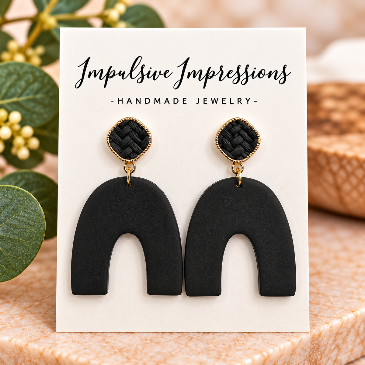 Matte black polymer clay arch earrings with black woven studs and gold-tone accents